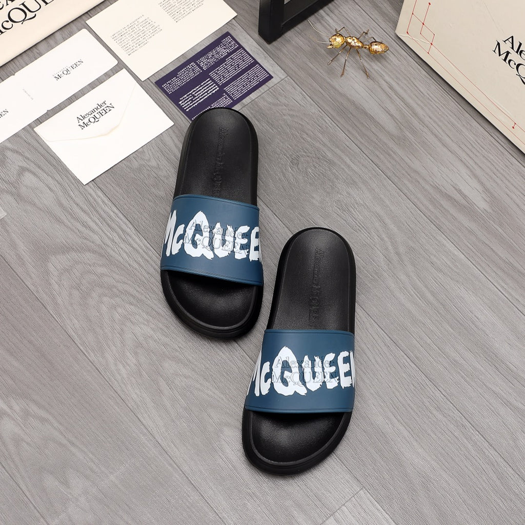 Black slide sandals with blue logo band and white lettering, pair view