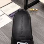 Black slide sandal with textured footbed and embossed logo text