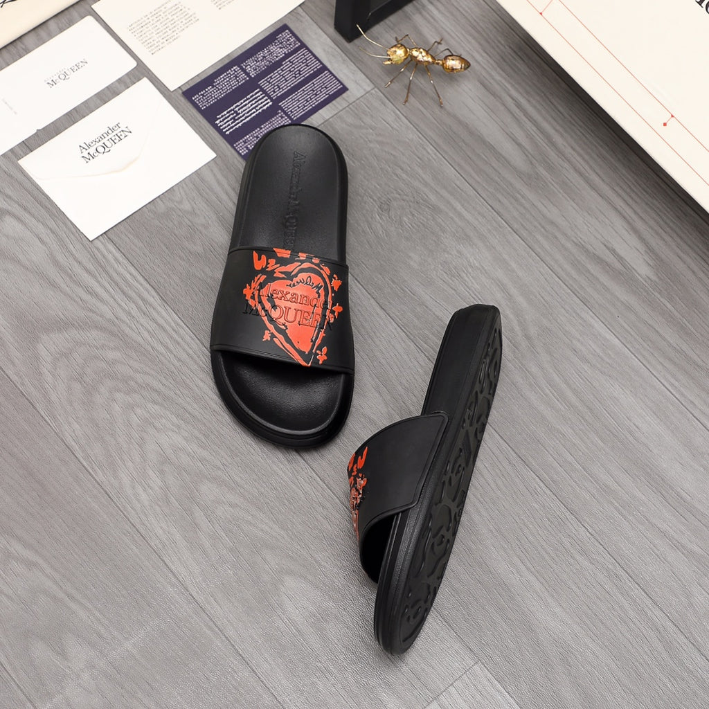 Black slide sandal pair with orange graphic logo on straps