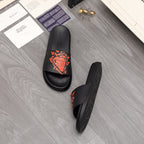 Black slide sandal pair with orange graphic logo on straps