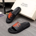 Black Alexander McQueen slide sandal with orange graphic logo on strap