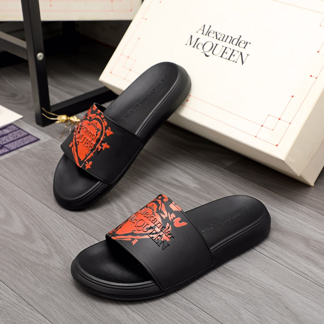 Black Alexander McQueen slide sandal with orange graphic logo on strap
