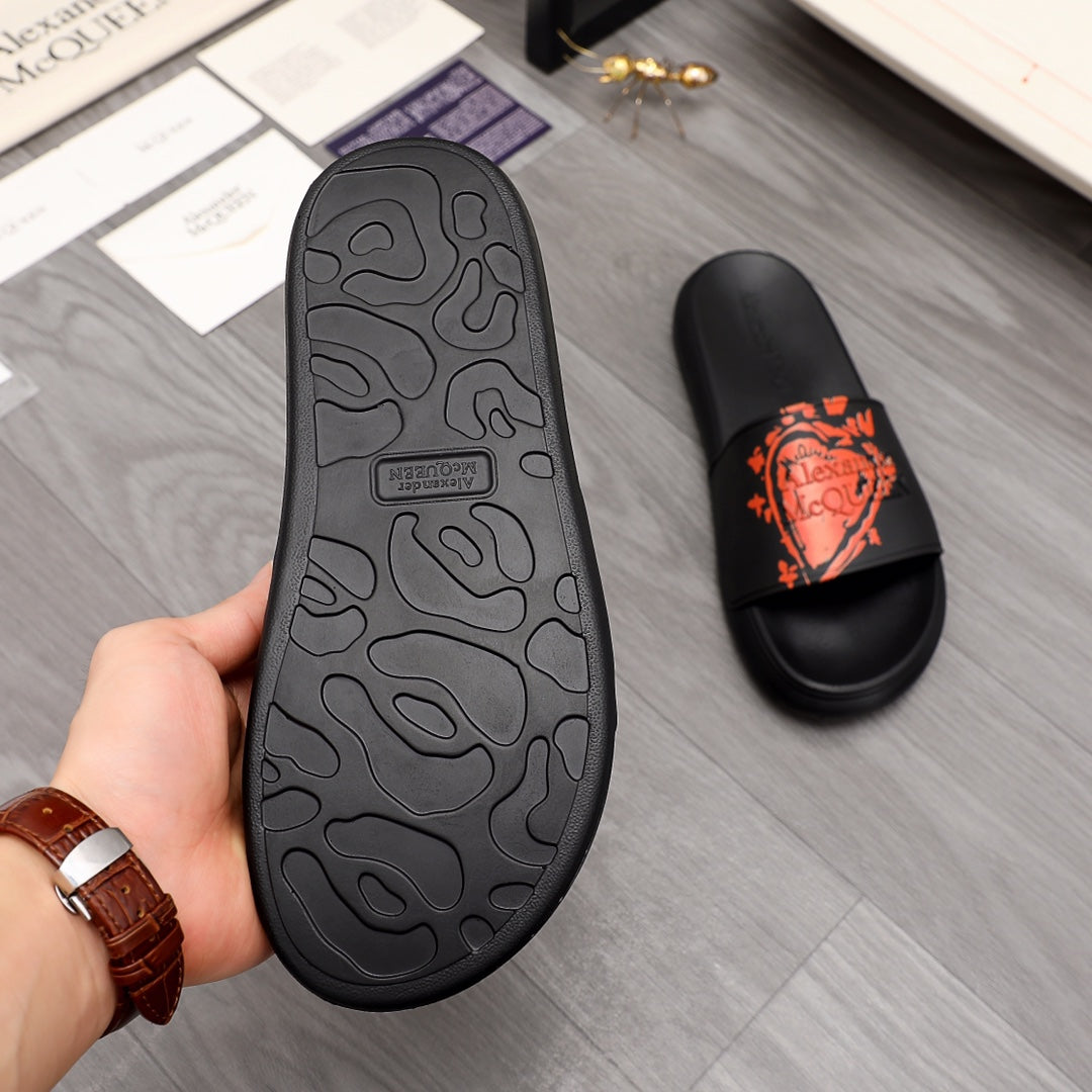 Black slide sandal outsole with orange logo on strap