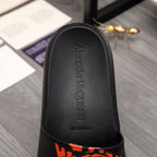 Black slide sandal footbed with printed brand text and orange trim