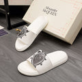 White slide sandals with black graphic emblem on the strap