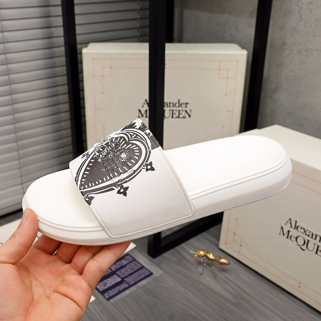 White slide sandals with black emblem print on the strap, side view