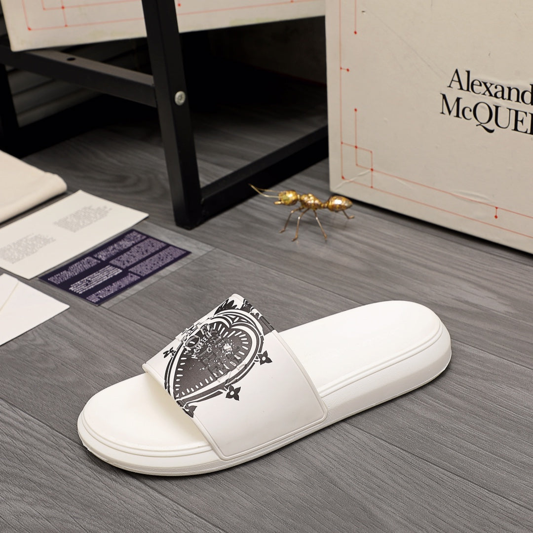 White slide sandals featuring a black emblem print on the front strap