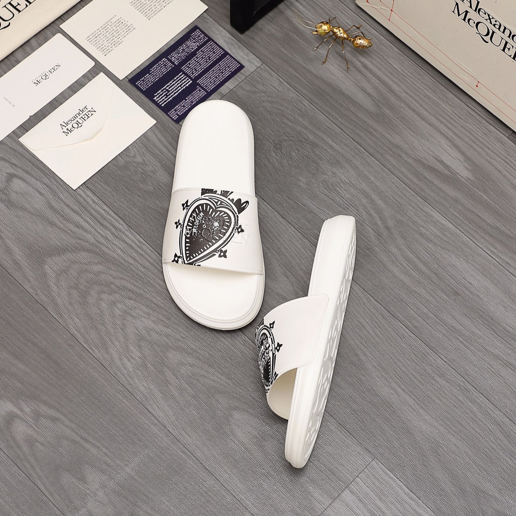 White slide sandals with black emblem print on the strap, pair view