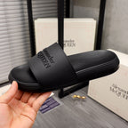 Black slide sandals with wide strap and embossed Alexander McQUEEN branding, close view