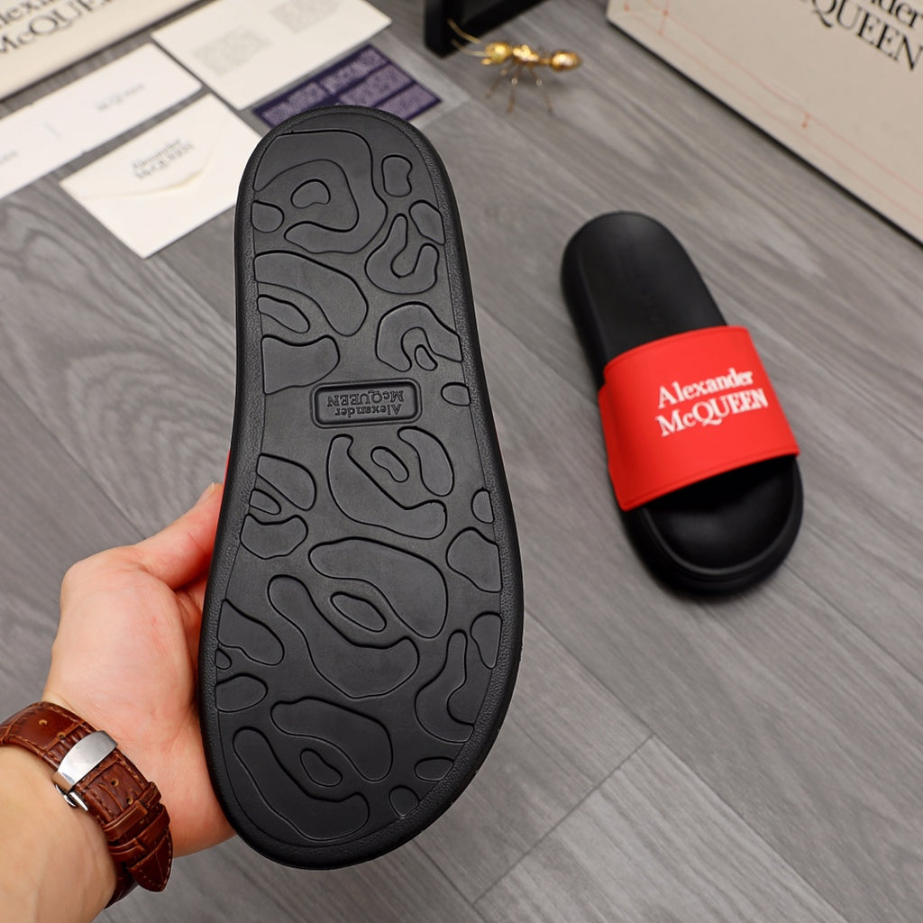 Black slide sandal outsole with red Alexander McQUEEN strap, underfoot view