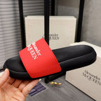 Black slide sandal with red Alexander McQUEEN logo strap, side view