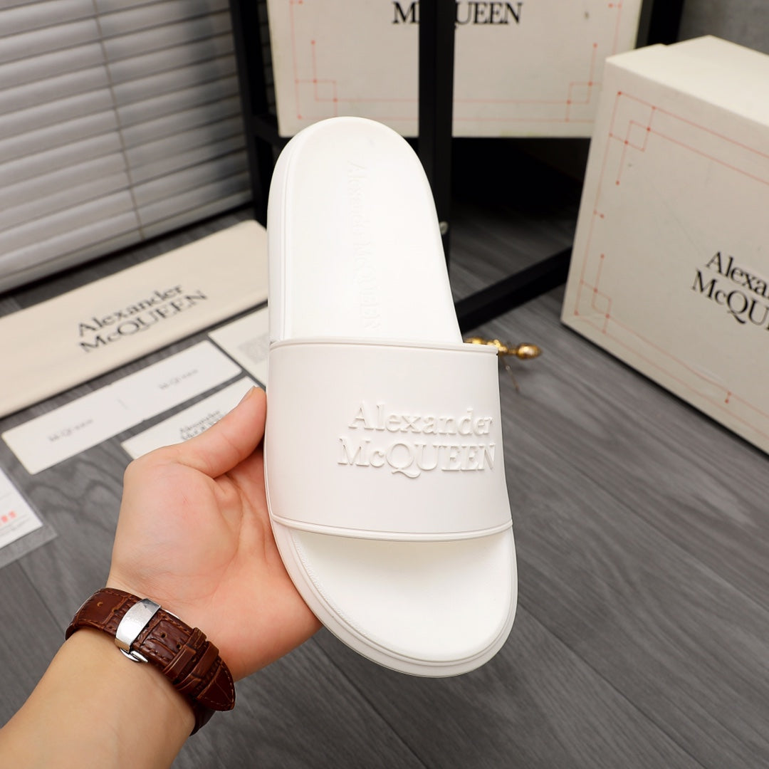 White slide sandal held in hand, wide strap with Alexander McQUEEN logo