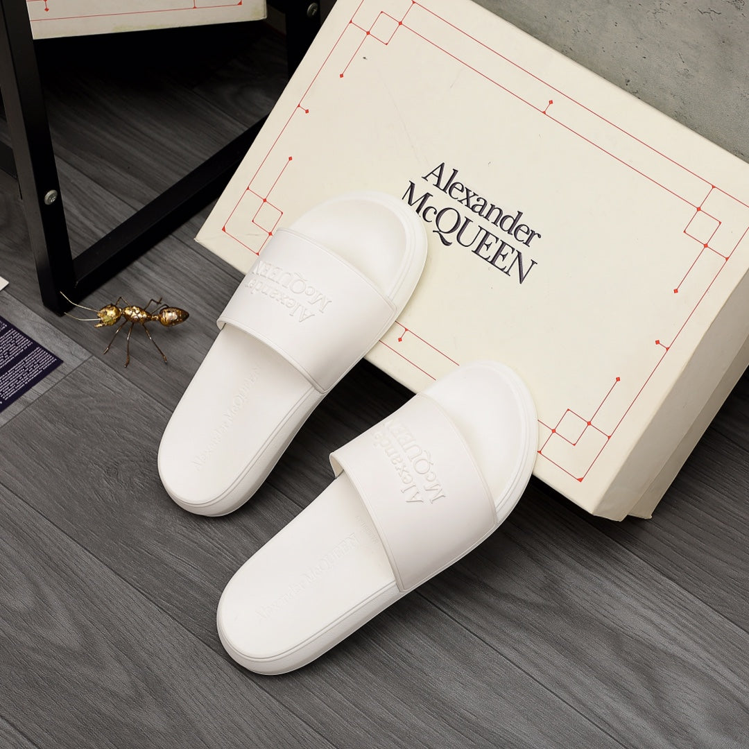 White slide sandals with wide front strap and embossed logo detail