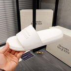 White slide sandals with wide strap and embossed logo on foot