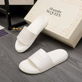 White slide sandals with wide strap and embossed logo detail