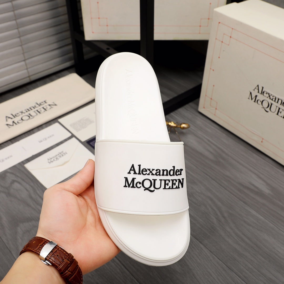 White slide sandal held in hand, Alexander McQUEEN logo on strap