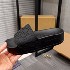 Black slide sandal with textured patterned strap and curved platform sole