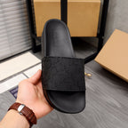 Black slide sandal with embossed footbed text and patterned strap