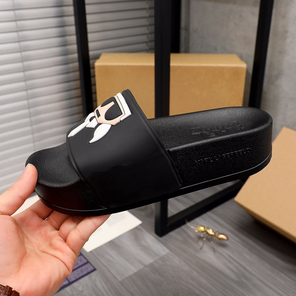 Black slide sandals with graphic face emblem on front strap, side angle