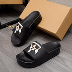 Black slide sandals with oversized graphic logo strap, cushioned footbed