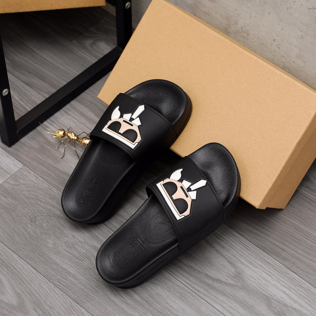 Black slide sandals pair with graphic face emblem on front straps