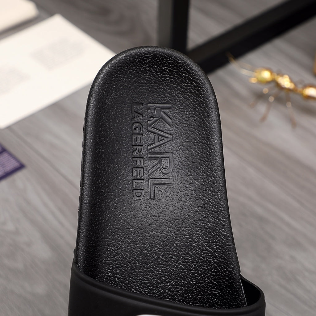 Black slide sandal outsole side with raised brand lettering on footbed