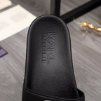 Black slide sandal outsole side with raised brand lettering on footbed