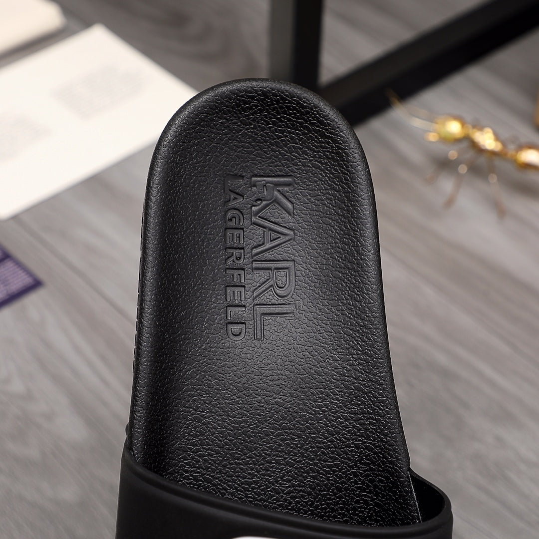 Black slide sandal outsole side with raised brand lettering on footbed