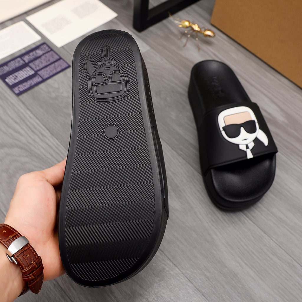 Black slide sandal outsole tread with raised icon and brand on textured surface