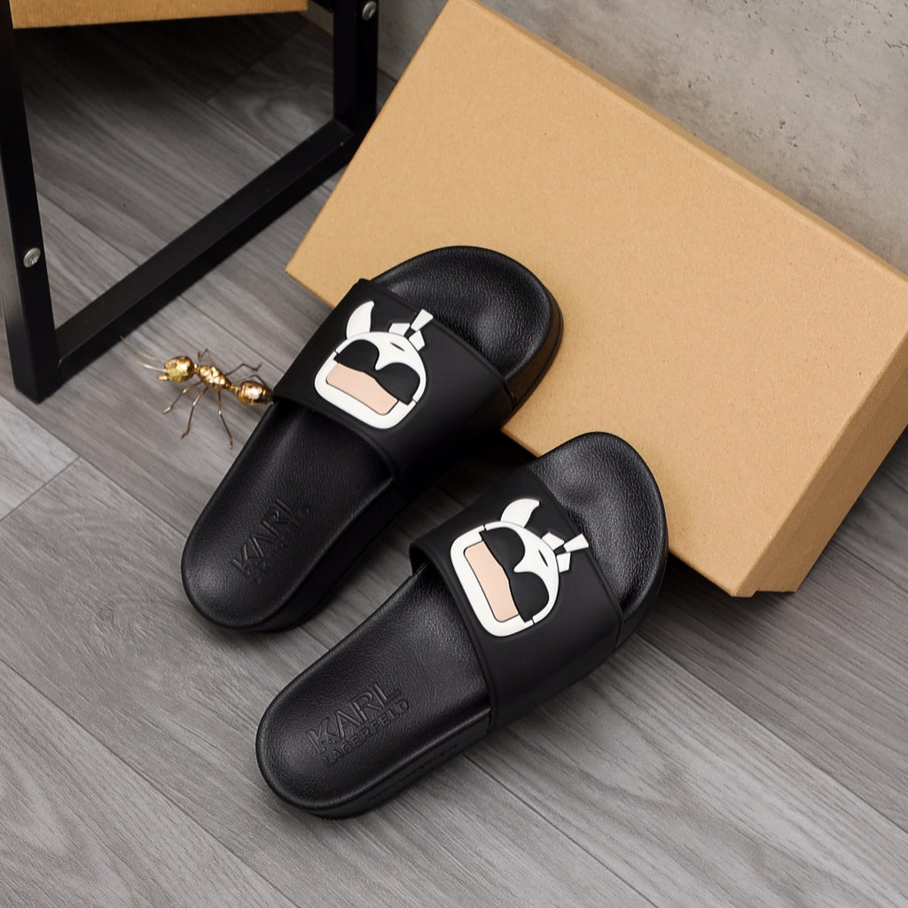 Black slide sandals pair with white character logo detail on top straps