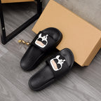 Black slide sandals pair with white character logo detail on top straps