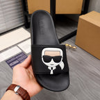 Black slide sandal with white character logo patch and branded footbed text