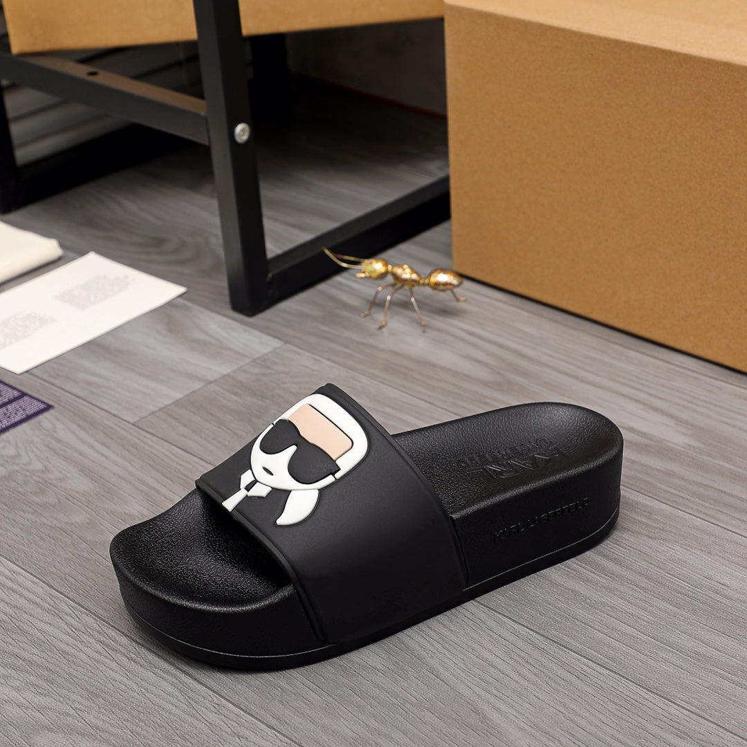 Black slide sandal with wide strap and white cartoon face graphic on top