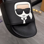 Black slide sandal close-up of white character logo patch on the strap