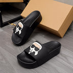 Black slide sandals with white cartoon logo strap and cushioned footbed