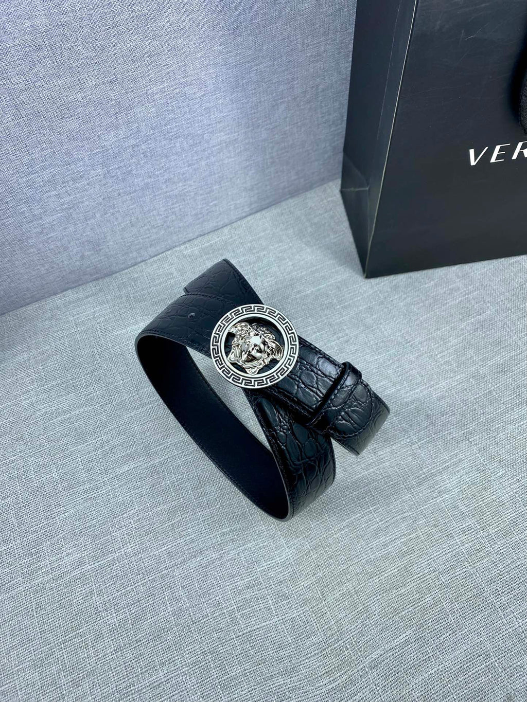 Black embossed leather belt with round Versace medallion buckle and folded end