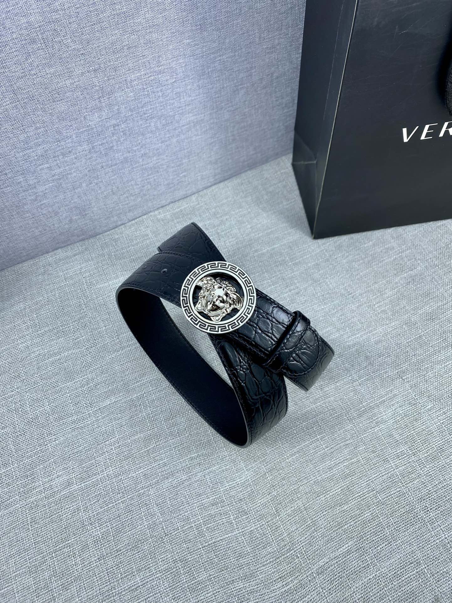 Black embossed leather belt with round Versace medallion buckle and folded end