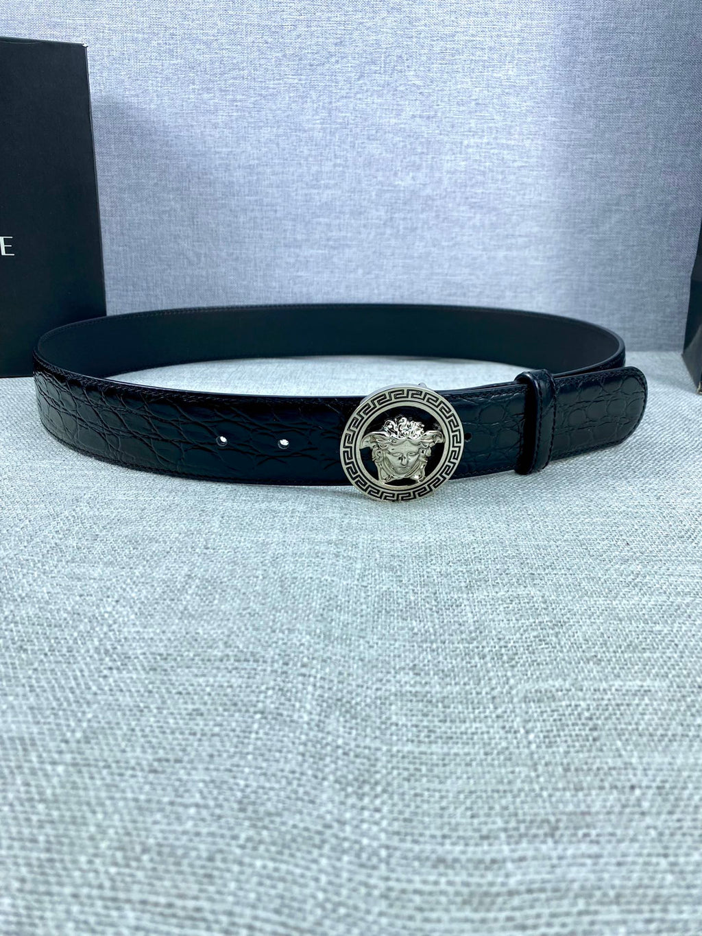 Black embossed leather belt with round Versace medallion buckle and adjustable holes