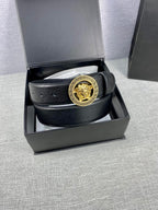Black leather belt with gold Medusa buckle, coiled inside a gift box.