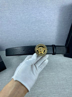 Black leather Versace belt with gold Medusa buckle on an adjustable strap.
