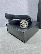 Black leather belt with gold Medusa buckle resting on a box.