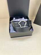 Dark leather belt with silver-tone ornate buckle inside gift box
