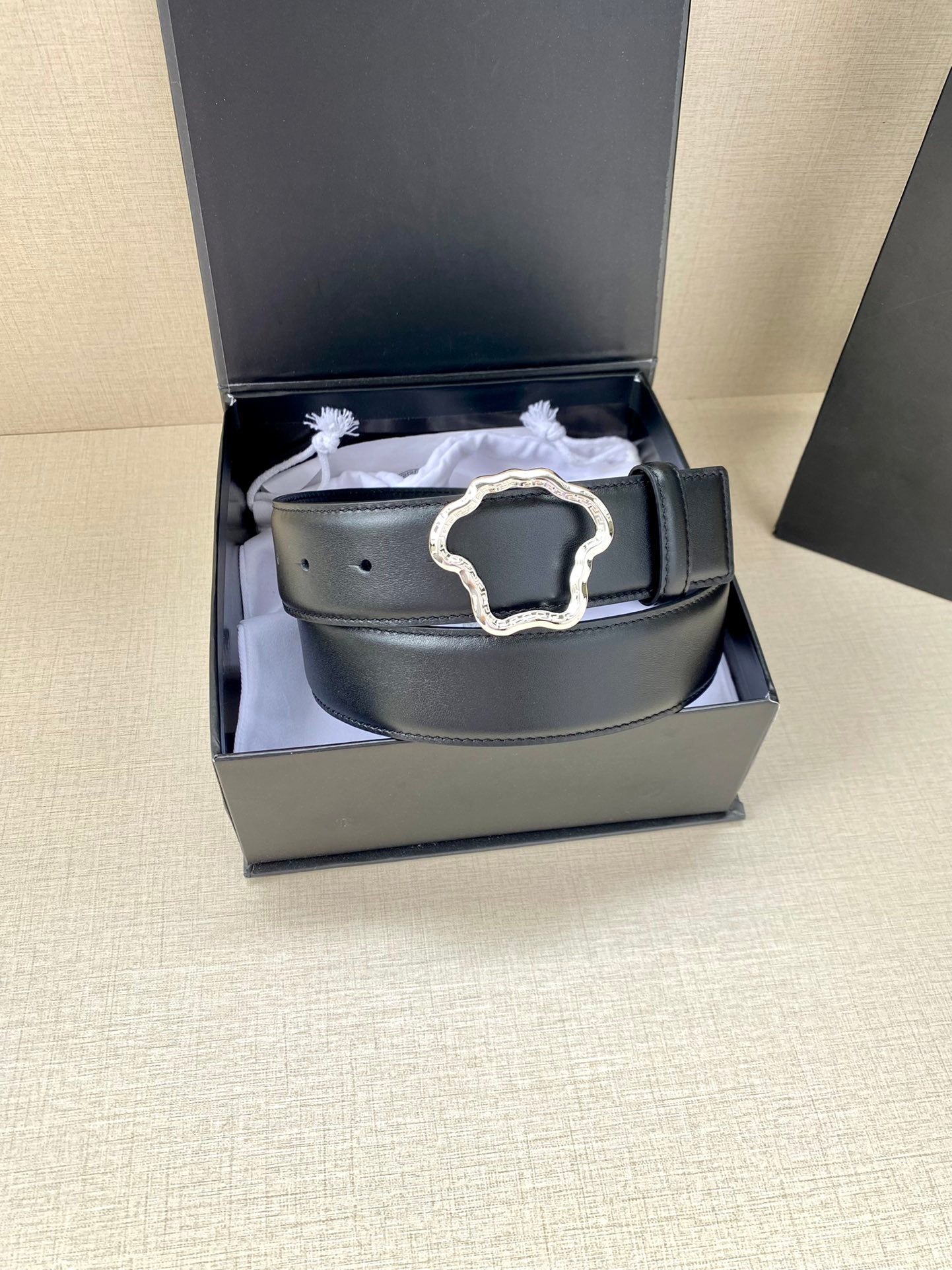 Dark leather belt with silver-tone ornate buckle inside gift box