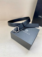 Dark leather belt with silver-tone ornate buckle on a box