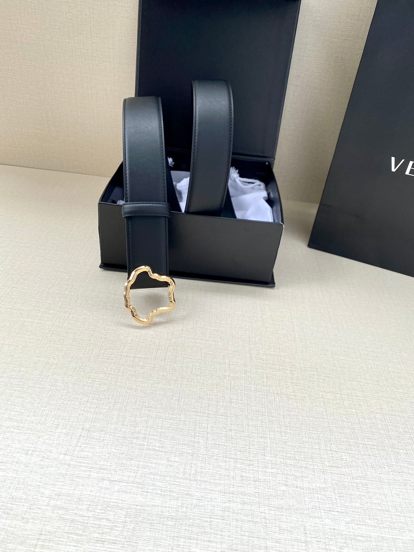 Black leather belt with gold-toned ornate buckle, strap ends upright