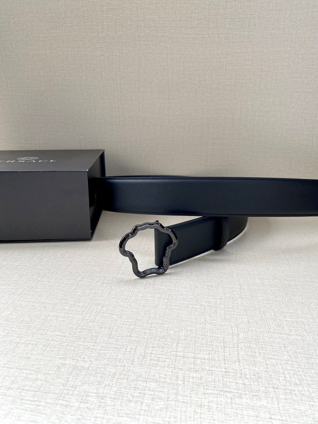 Black leather belt with silver-toned ornate buckle, side view