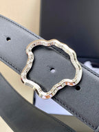 Black leather belt with silver-toned ornate buckle close-up