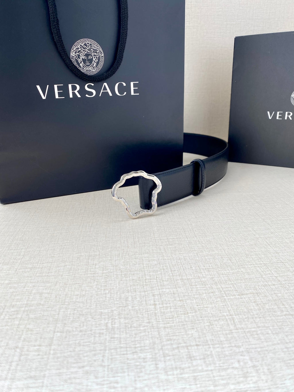 Navy leather belt with silver-tone Medusa-shaped buckle and stitched edges