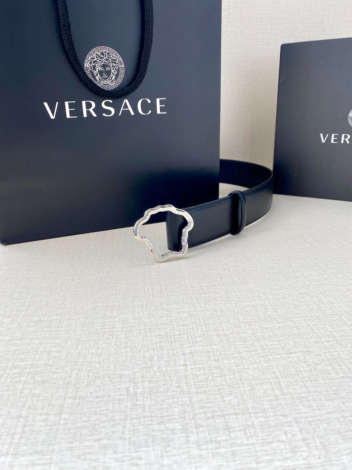 Navy leather belt with silver-tone Medusa-shaped buckle and stitched edges