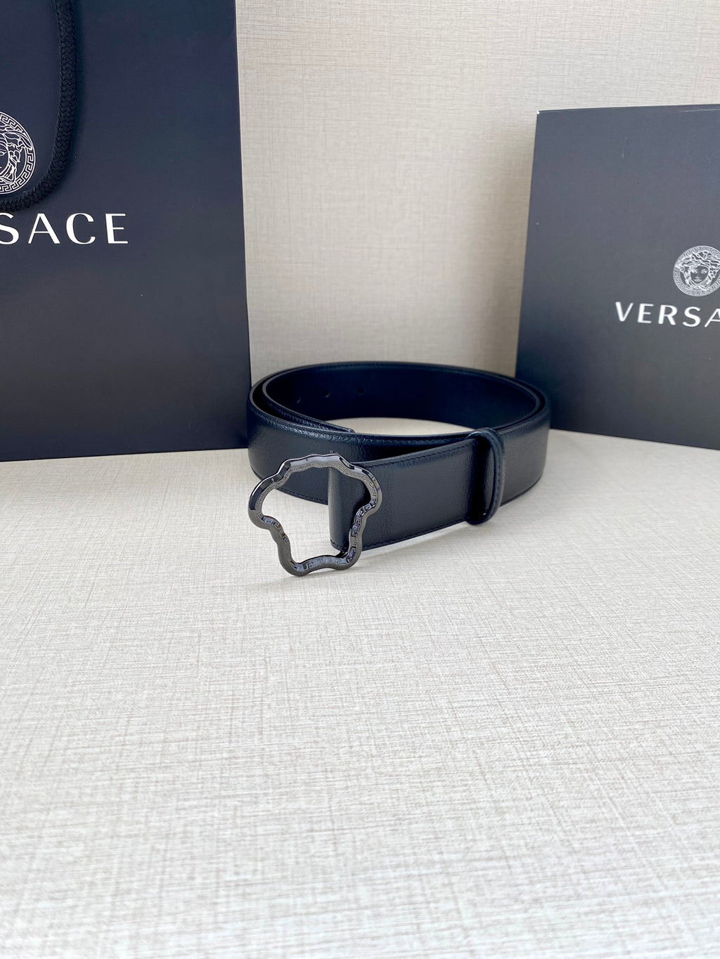 Dark blue leather belt with silver-tone Medusa-shaped buckle and perforated strap